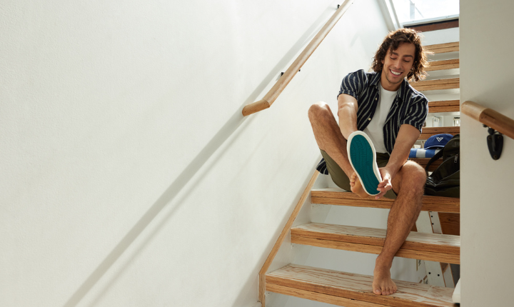 Man on stairs, putting on his Vessi Boardwalk Slip-Ons in Sail White.