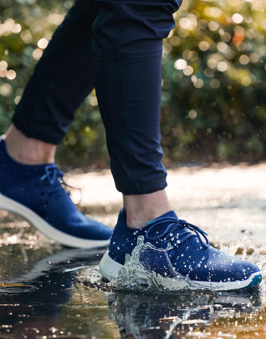 man walking through a puddle of water with waterproof sneakers